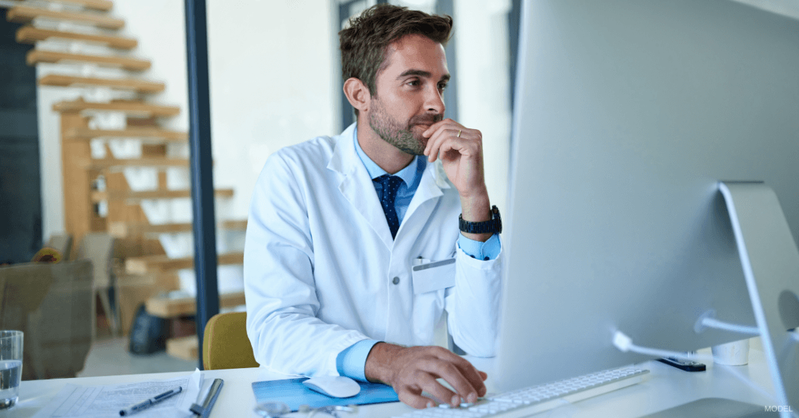 Doctor looking at computer and examining PPC performance results (model)