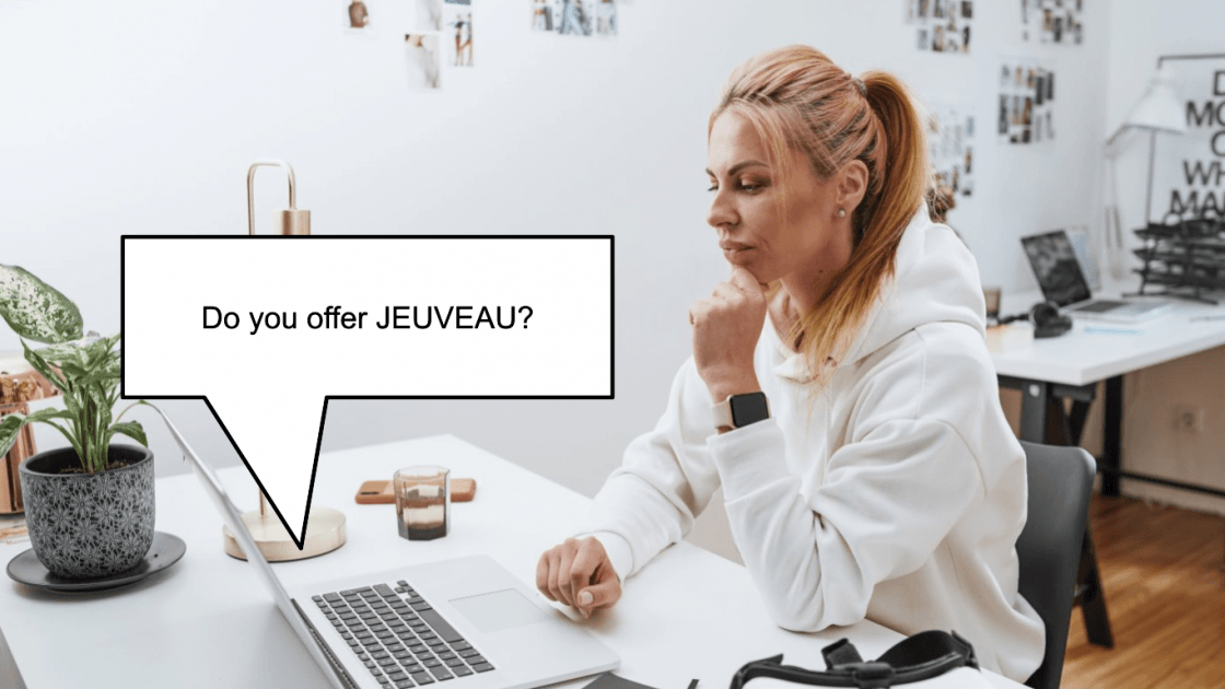 Woman looking at her laptop with the pop up of "Do you offer JEUVEAU?" (model)